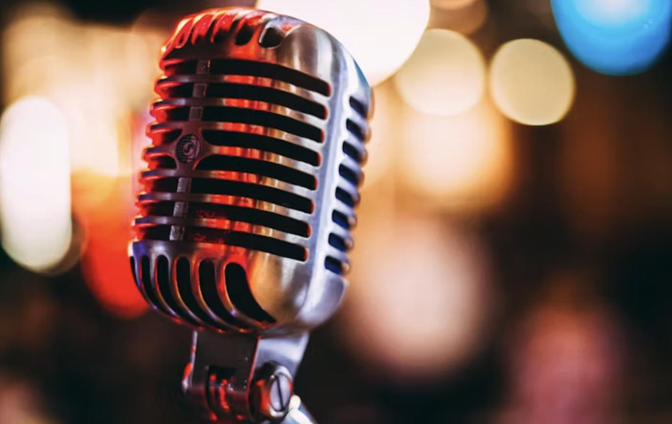 Vintage microphone in close-up with warm bokeh stage lights in the background