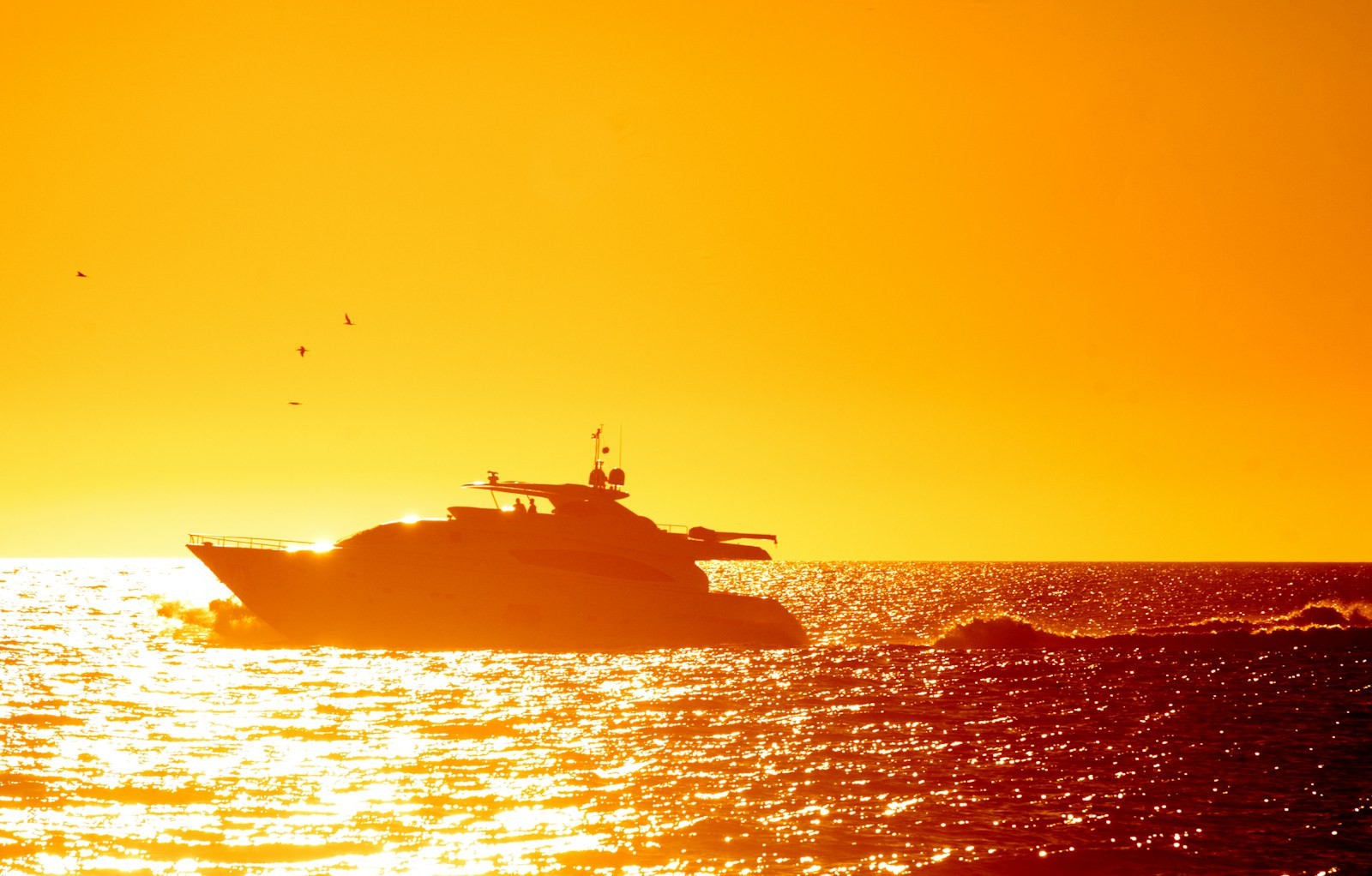 A superyacht silhouetted against a golden Lagos sunset as guests take their seats on deck for the chef's table